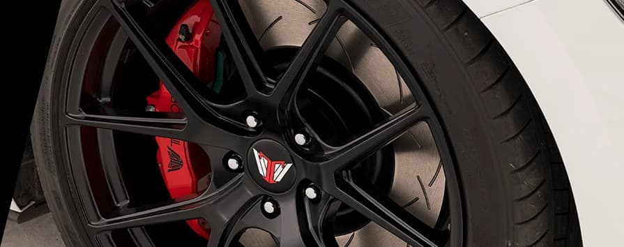 Système de freinage DBA haute performance avec disque rainuré et étrier Système de freinage haute performance avec disque rainuré DBA et étrier rouge visible à travers les rayons de roue noire