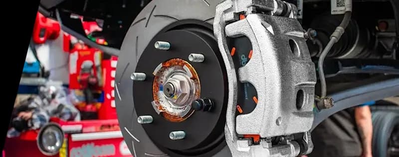 Installation de système de freinage DBA haute performance avec disque rainuré et composants d'étrier Gros plan sur système de freinage performant montrant un disque rainuré DBA installé sur véhicule avec étrier argenté et moyeu visible