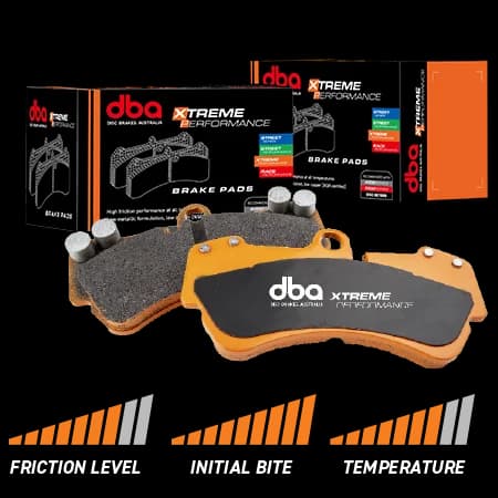 Plaquettes DBA Xtreme Performance conçues pour un freinage constant à haute température dans les applications performantes et intensives Plaquettes DBA Xtreme Performance avec plaques de support oranges et matériau de friction présentées à côté de la boîte d'emballage